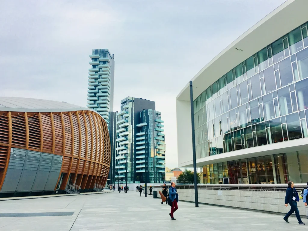 Modern architecture with curved wooden building, glass skyscrapers, and contemporary office building in a city square.